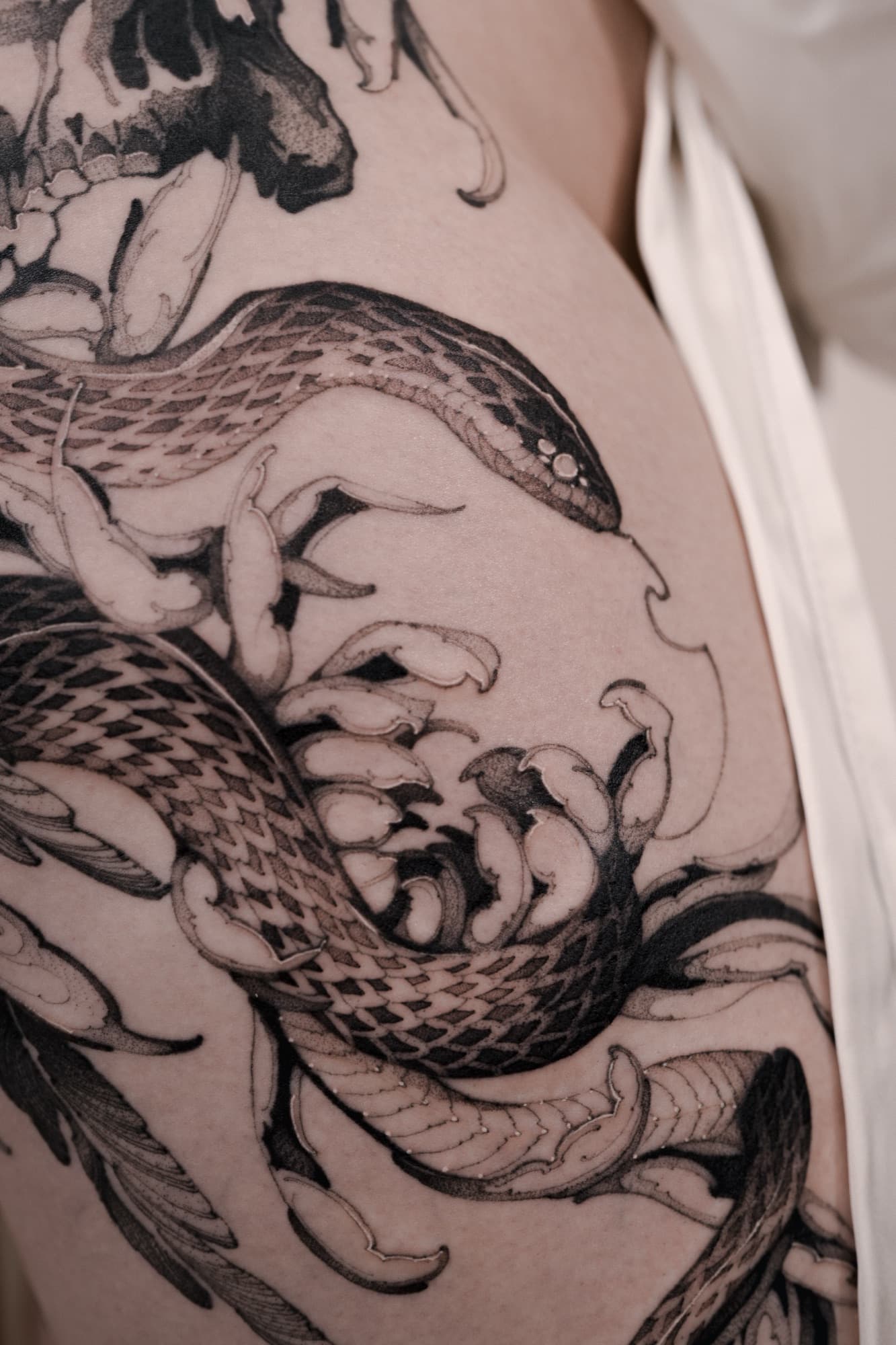 Skull, snake and floral tattoo covering the hip and thigh