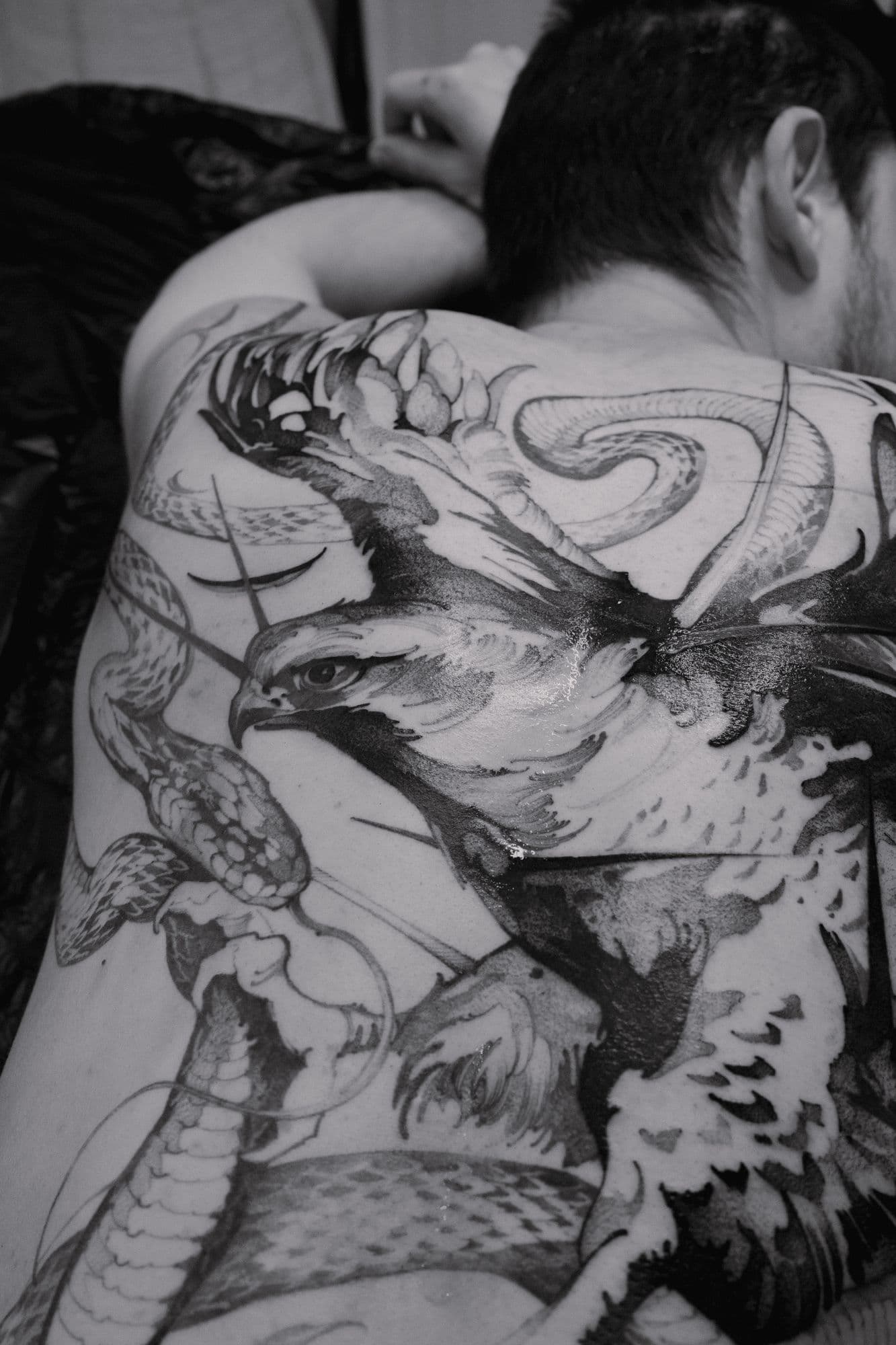 Large-scale falcon and snake tattoo covering the back