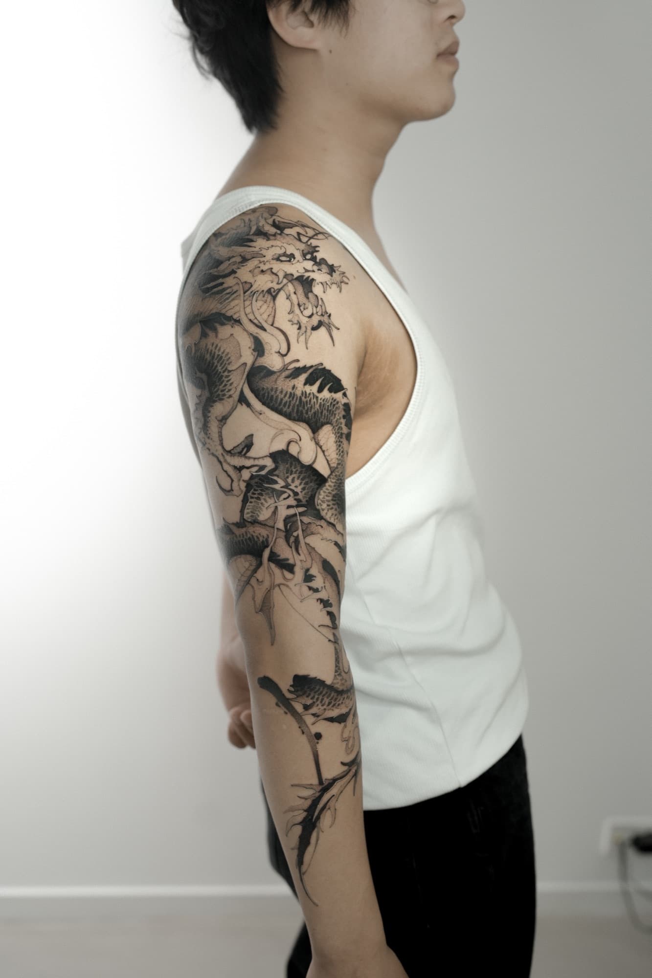 Black and grey dragon tattoo covering the upper arm and shoulder