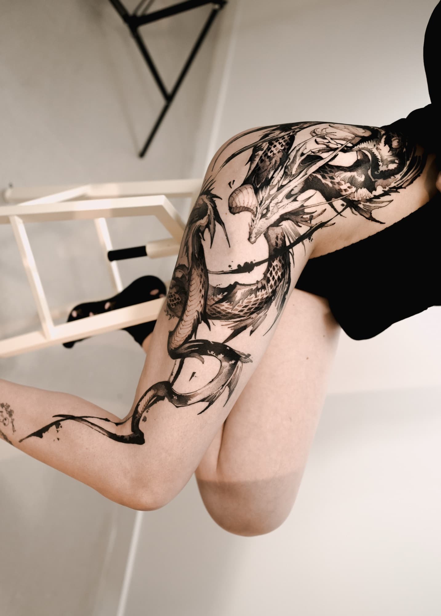 Bold black dragon tattoo covering the thigh and hip