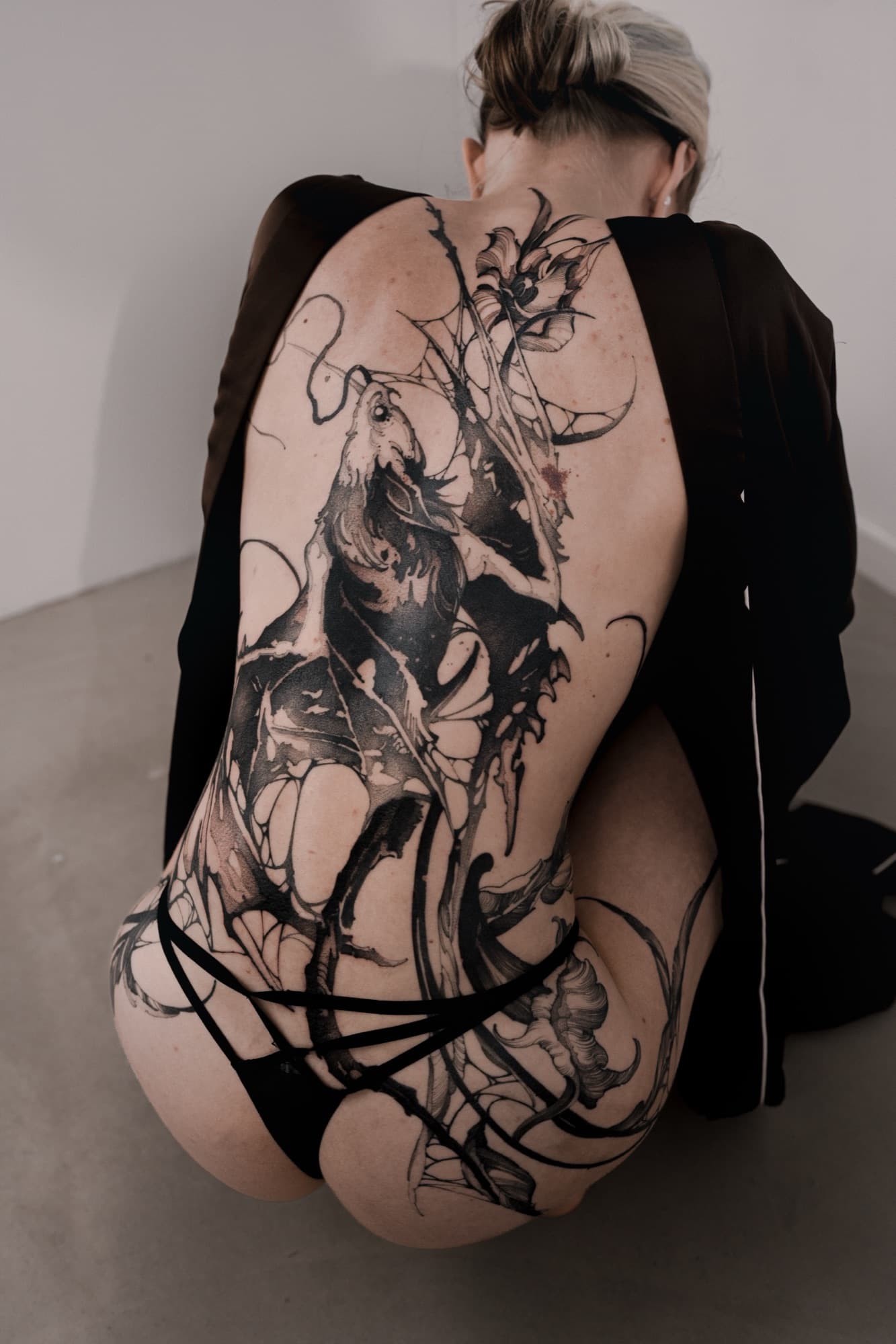 Large-scale creature tattoo covering the back and hip
