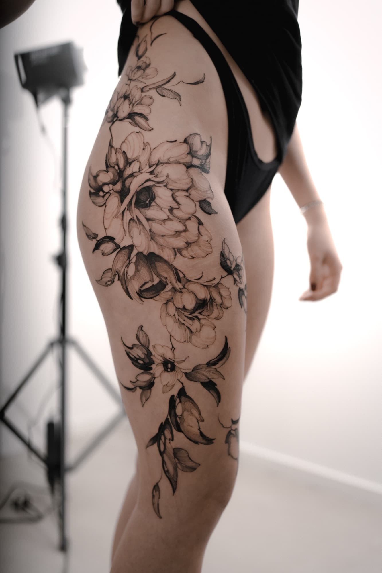 Fine-line peony flowers tattoo on the thigh and hip