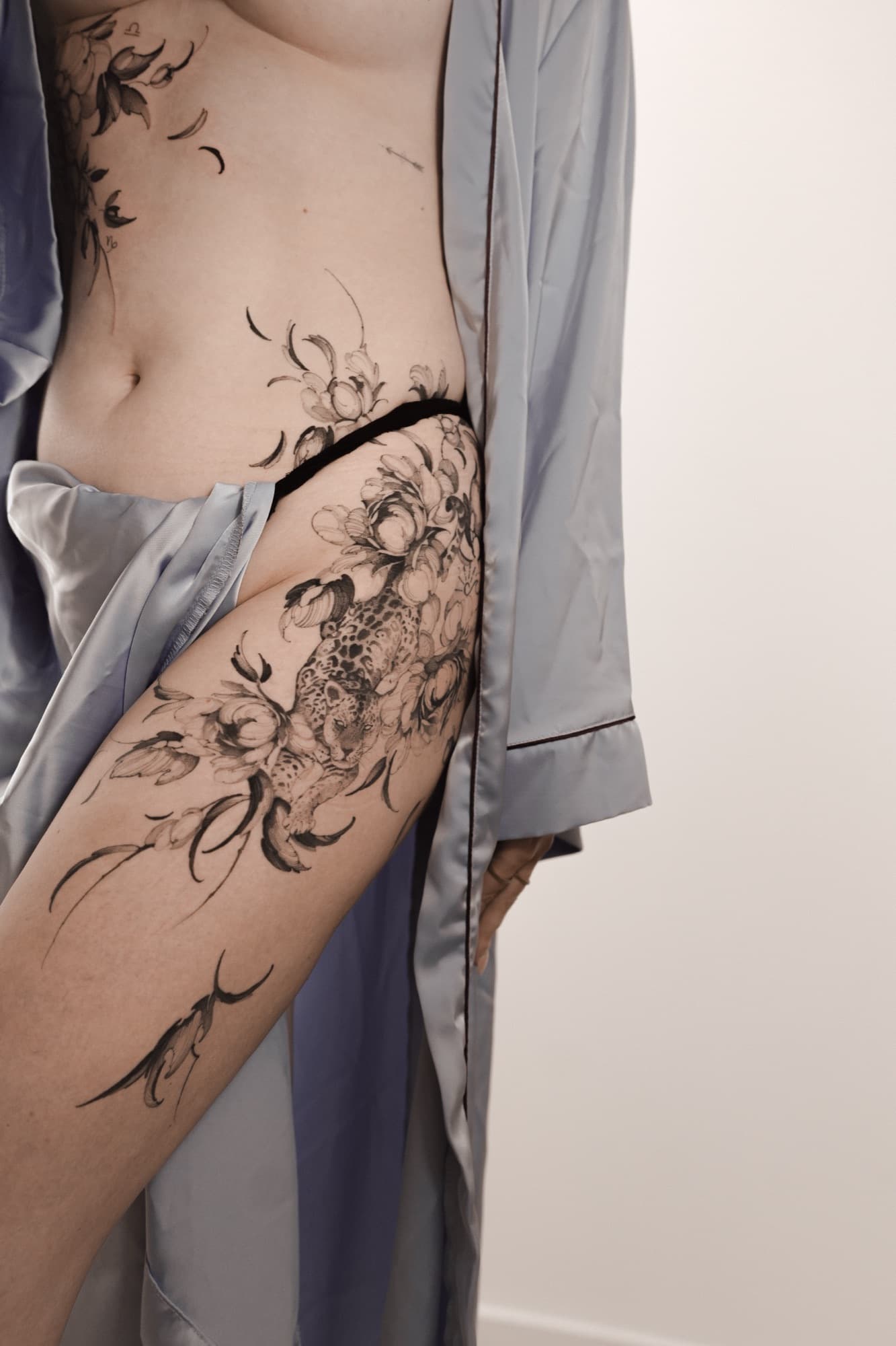 Snake and floral tattoo flowing down the leg