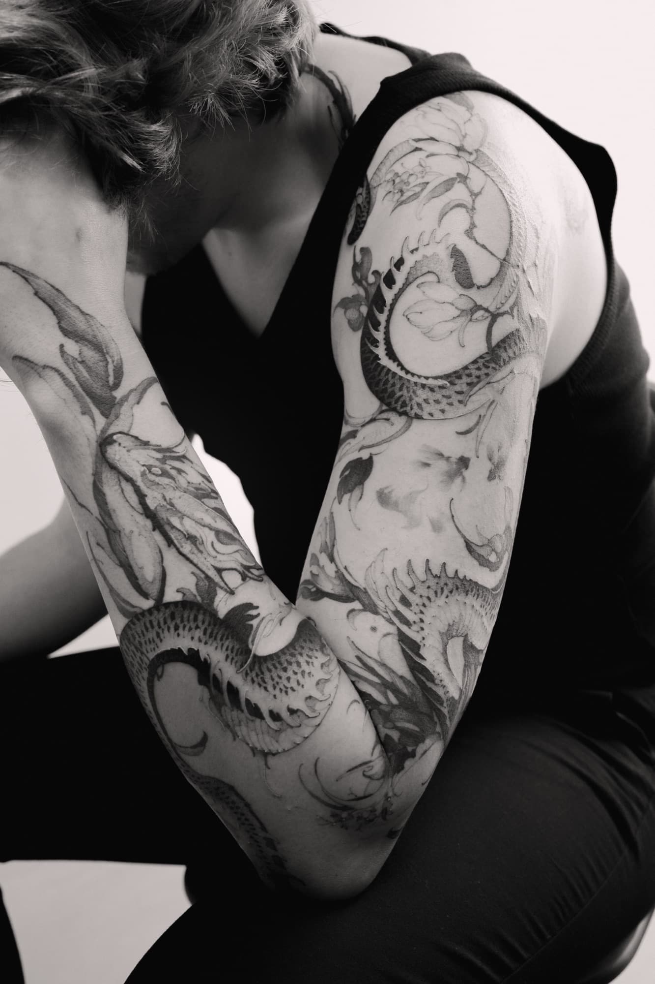 Matching dragon tattoos on both arms, fine black linework