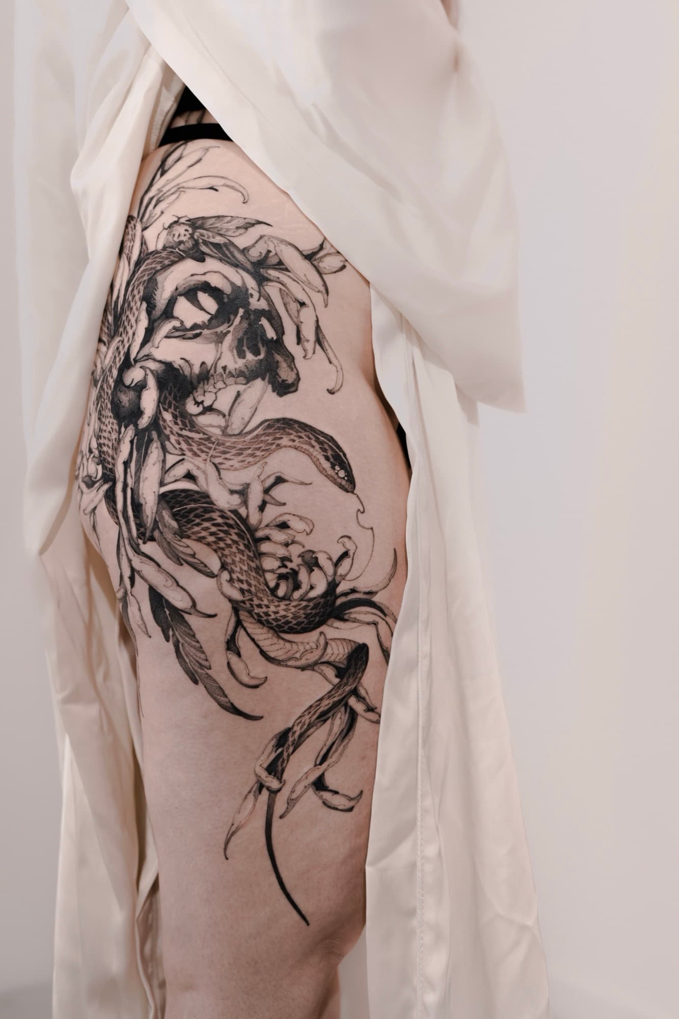 Detail of skull and snake tattoo linework on the thigh