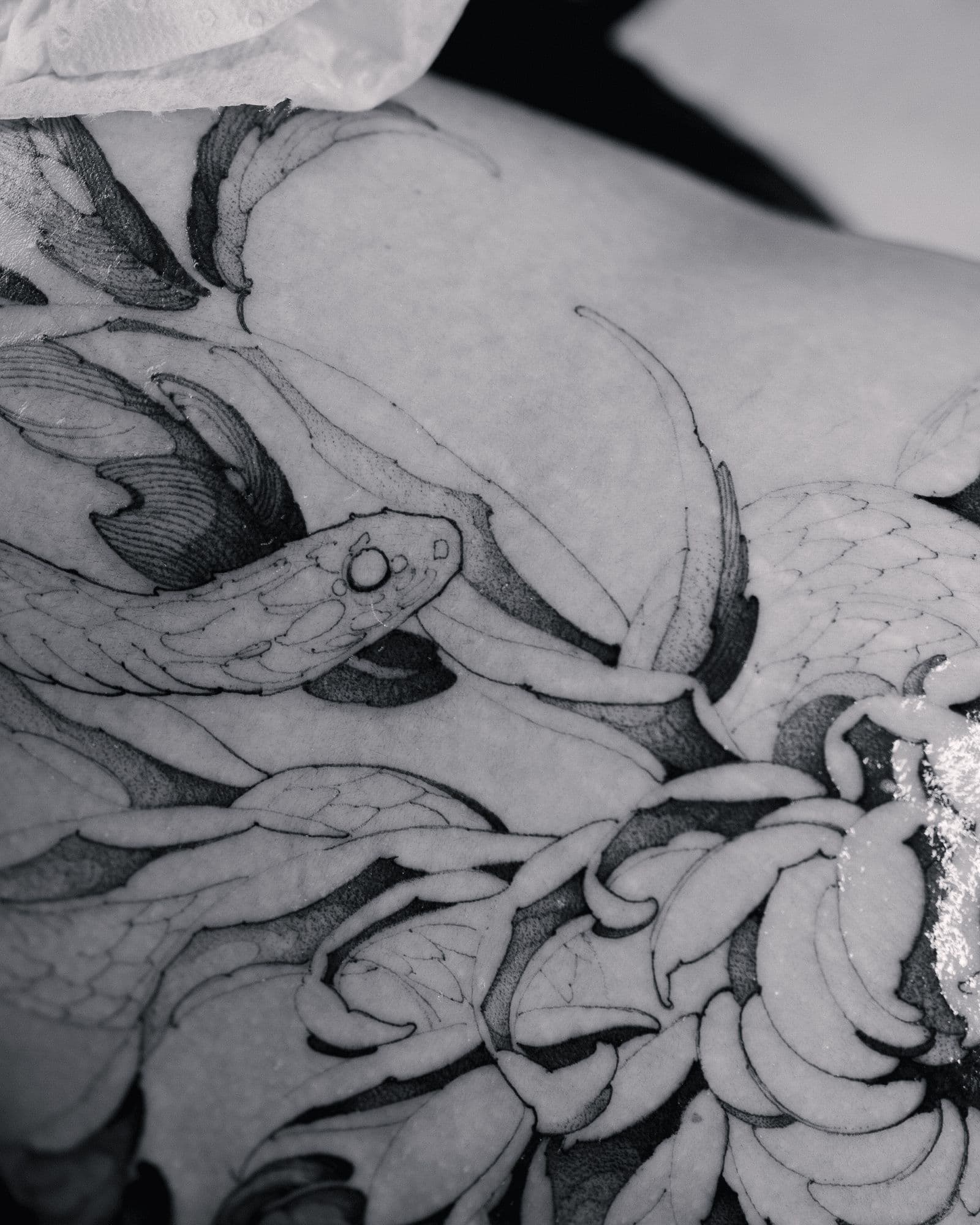 Snake and chrysanthemum tattoo detail on the forearm