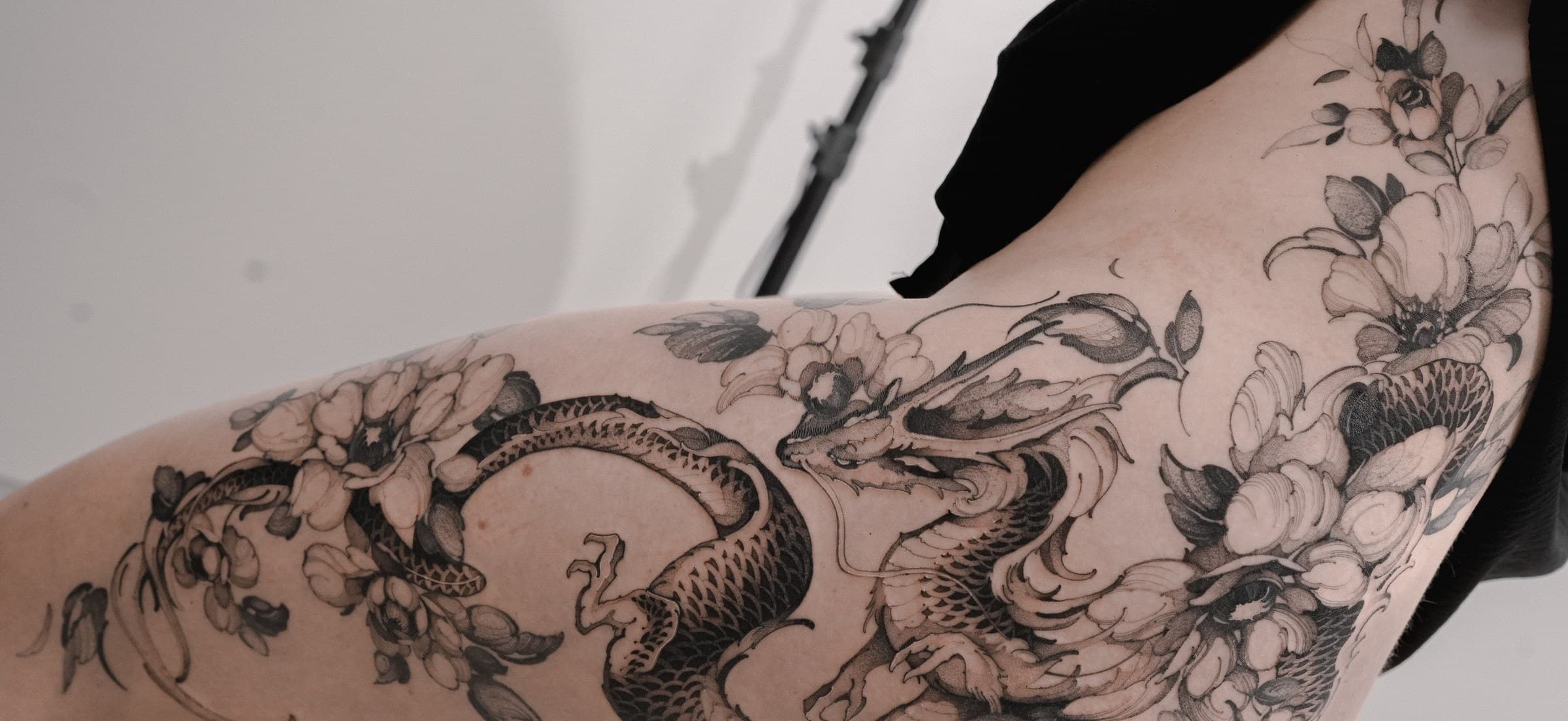 Dragon and peony flowers tattoo flowing along the thigh